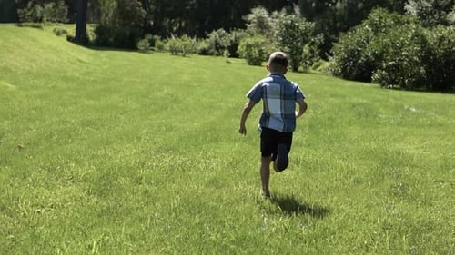 An Attractive Boy Runs Along the Grass in the Park Having a Good Mood in the Summer