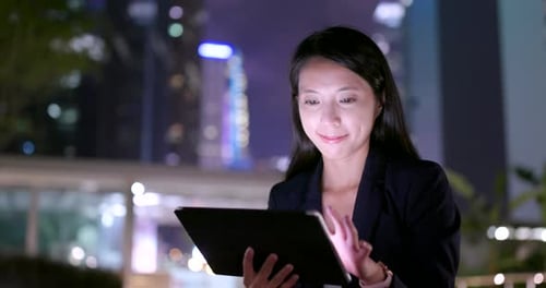 Businesswoman Works on Tablet at Night in City