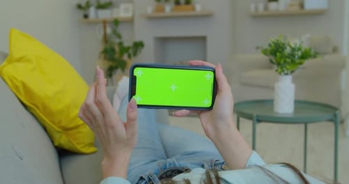 Girl Using Smartphone in Horizontal Landscape Mode with Green Screen in Living Room Watching Movie