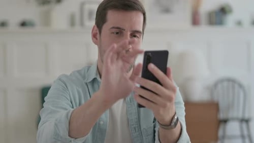 Man Celebrates Good News on Phone Indoors