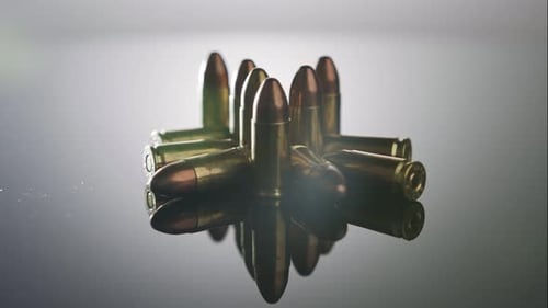 Waffenkontrolle. Munition aus 9-mm-Kugeln, die sich auf einer reflektierenden Oberfläche
drehen