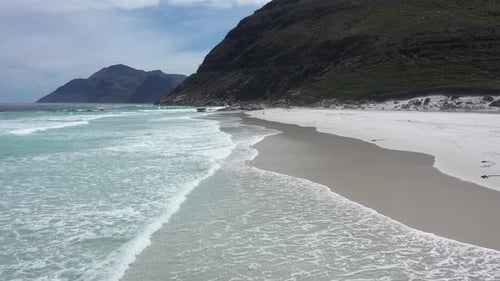 Closeup Flight Over Sandy Beach and Calm Blue Wave