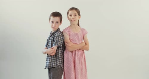 Two young kids smiling and laughing on a white studio background