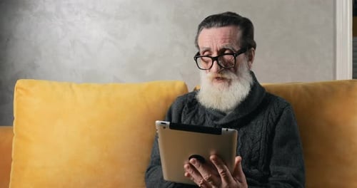 Senior Man Using Tablet at Home on Couch