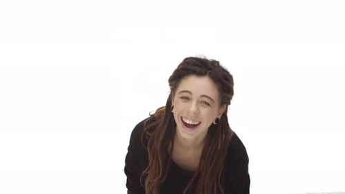 Attraktive kaukasische Frau mit Dreadlocks und Ohrtunneln, die über etwas Lustiges anfängt zu lachen