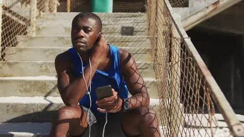 Fit Man on Steps with Phone and Earbuds