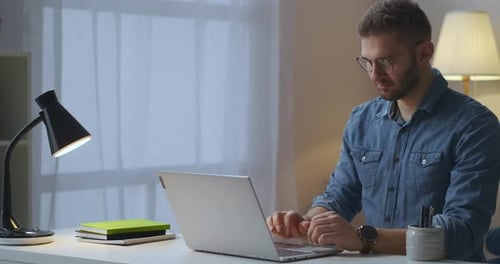 Man Works at Laptop in Home Office