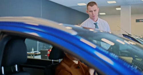 O consultor vendedor está ao lado de um carro novo