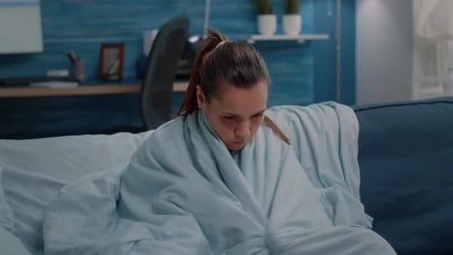 Femme malade qui a froid et qui a des frissons à cause de la maladie