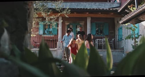 Group of young friends enjoying wine in front of a mediterranean house