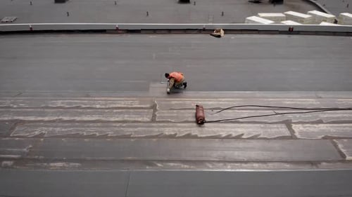 Travailleurs sur un chantier de construction. Le processus d'isolation hydraulique de la toiture. Avec l'aide d'un