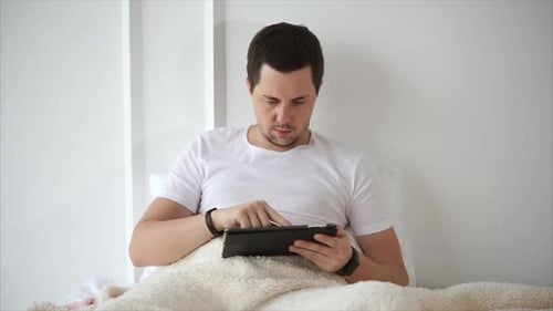 Man in Bed Using Tablet Device