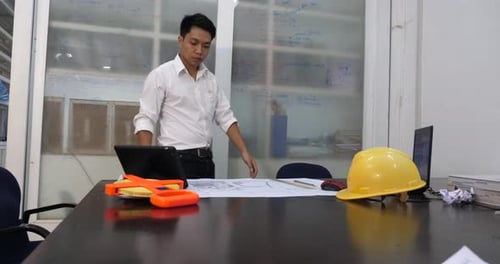 Asian Architect Working With Blueprint