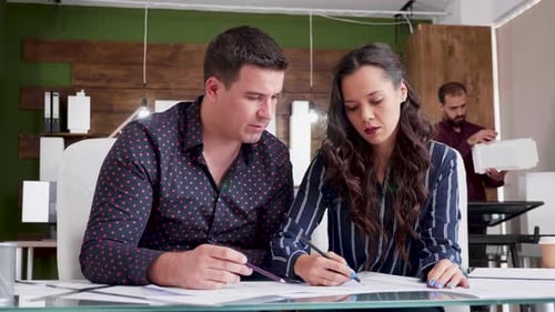 Young Man and Woman Working As Architects with Blueprints