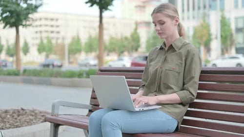 Woman Typing on Laptop in Urban Park