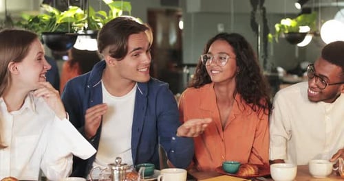 Four Young Adults Talking Together at Cafe