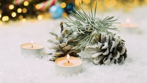 Falling Down Snow on the Pine Cones Fir Branch and Candles on the Christmas Background