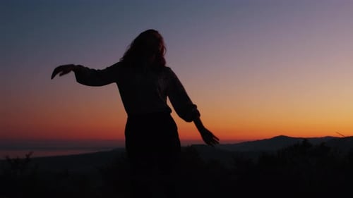 Woman with Arms Outstretched at Sunset