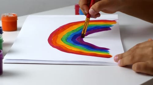 Child Painting Rainbow with Paint Brush and Colors