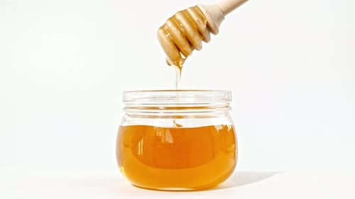 Honey Dripping Pouring From Special Honey Spoon in Glass Bowl