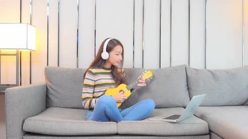 Woman Playing Ukulele with Laptop at Home