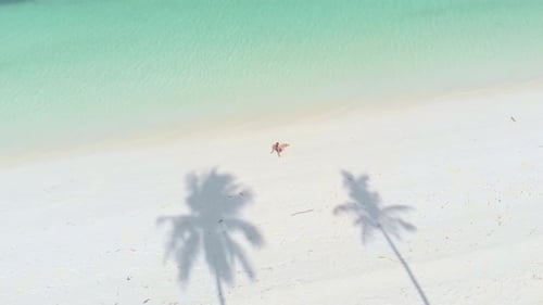 Aerial: Woman relaxing on white sand beach turquoise water tropical coastline
