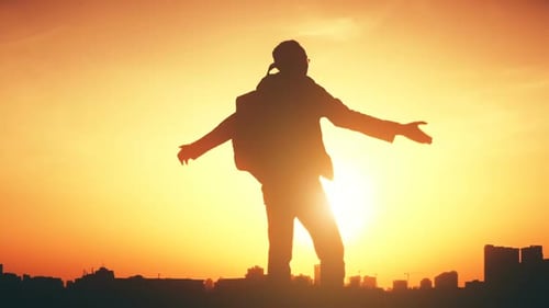 Silhouette Standing Arms Outstretched at Warm Sunrise