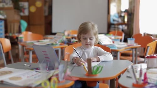 Child Writes at Desk in Classroom