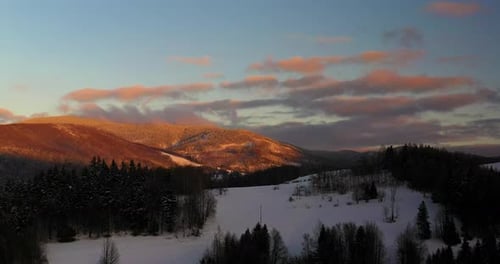 Aerial View of Mountains and Forest Covered with Snow at Sunset in Winter
