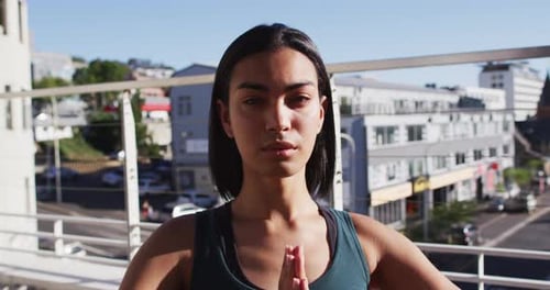 Porträt einer geschlechtsspezifischen Person gemischter Rassen, die Yoga-Meditation auf der Dachterrasse praktiziert