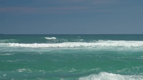 Azure Ocean with Rolling Waves Against Blue Sky Slow Motion