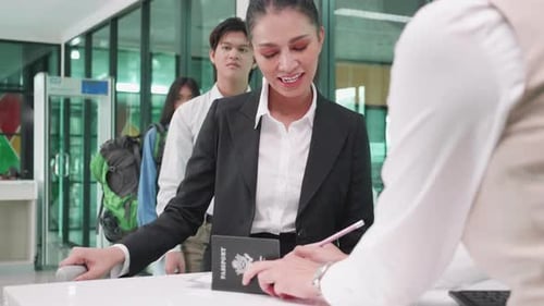 Asian businesswoman gets tickets from airline staff at the check-in counter at airport
