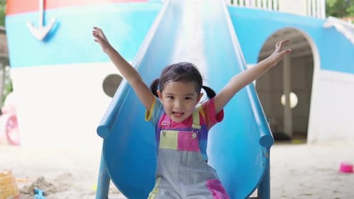 4K Little Asian girl sliding and playing at playground in the park