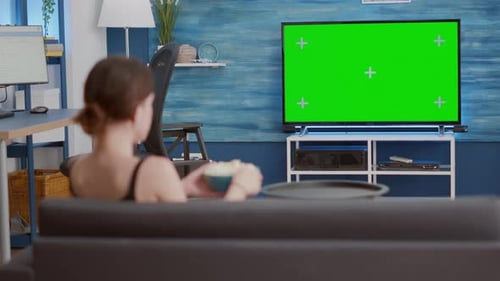 Static Tripod Shot of Young Woman Watching Movie on Tv with Green Screen and Eating Popcorn