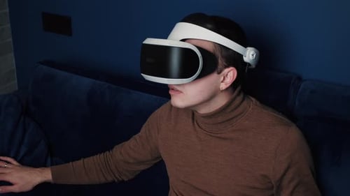 Young Adult Using VR Headset on Sofa