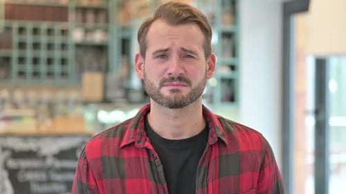 Porträt eines verärgerten jungen Mannes, der vor der Kamera w
