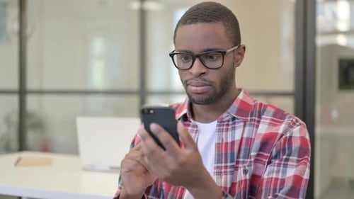 Worried Adult Man Looks at Phone in Office