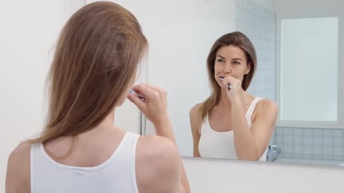 Cheerful Woman Brushing Teeth in a Clean Bathroom