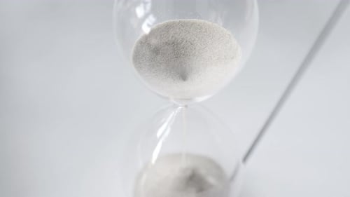 Sand Falling in Hourglass on White Surface