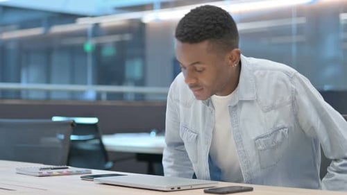 Young Adult Opens Laptop in Modern Office