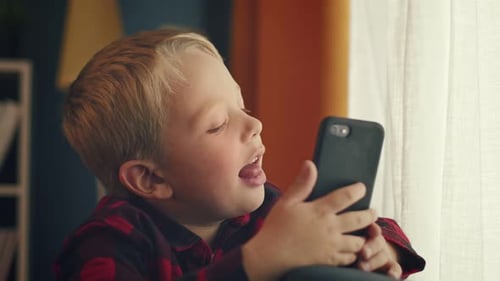 Smiling Boy Using Mobile Phone Indoors