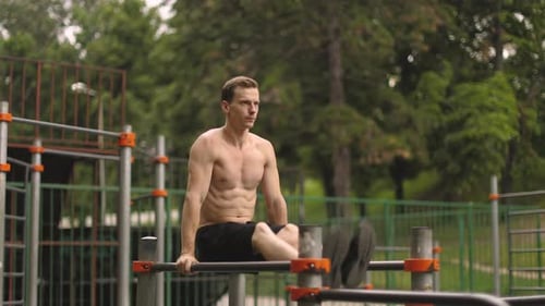 Muscular Man Exercising on Parallel Bars