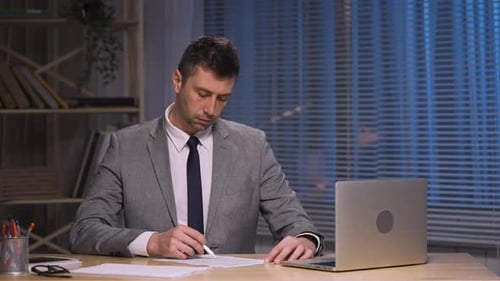 Professional Man Writing at Desk Late at Night