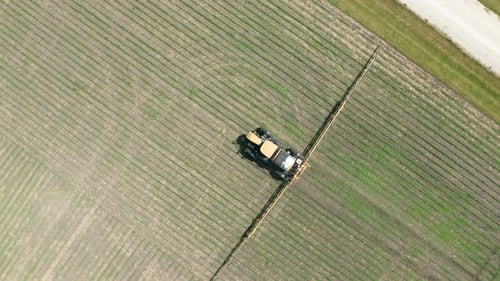 Aerial top down, tractor with pesticide spraying attached driving on farm field. Series