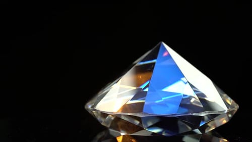 Diamant schimmert mit blauen und orangefarbenen Reflexen. Schwarzer Hintergrund