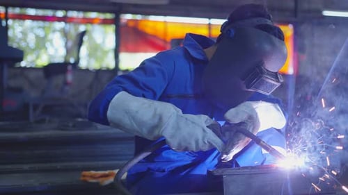 asian male technician worker in a dressed in protective uniform welding metal frame