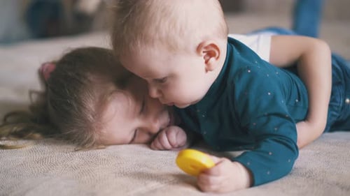 Baby Hugs Girl Lying Down Together Indoors