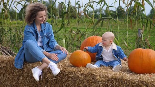 Woman and Baby Enjoying a Fall Day With Pumpkins