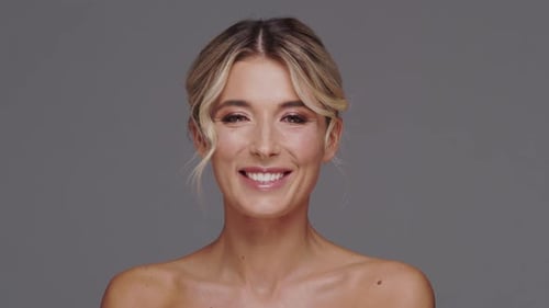 Studio portrait of young and beautiful blond woman over grey background.