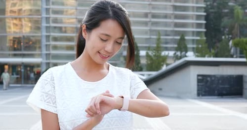 Woman Checks Smartwatch in Urban Environment